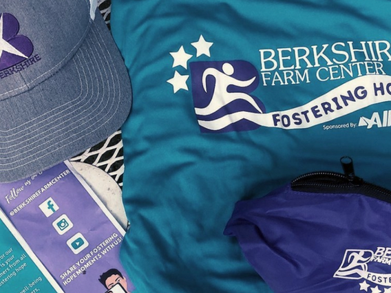 Assorted promotional items including a cap, t-shirts, and pamphlets from berkshire farm center, themed in blue and purple colors with logos and text.