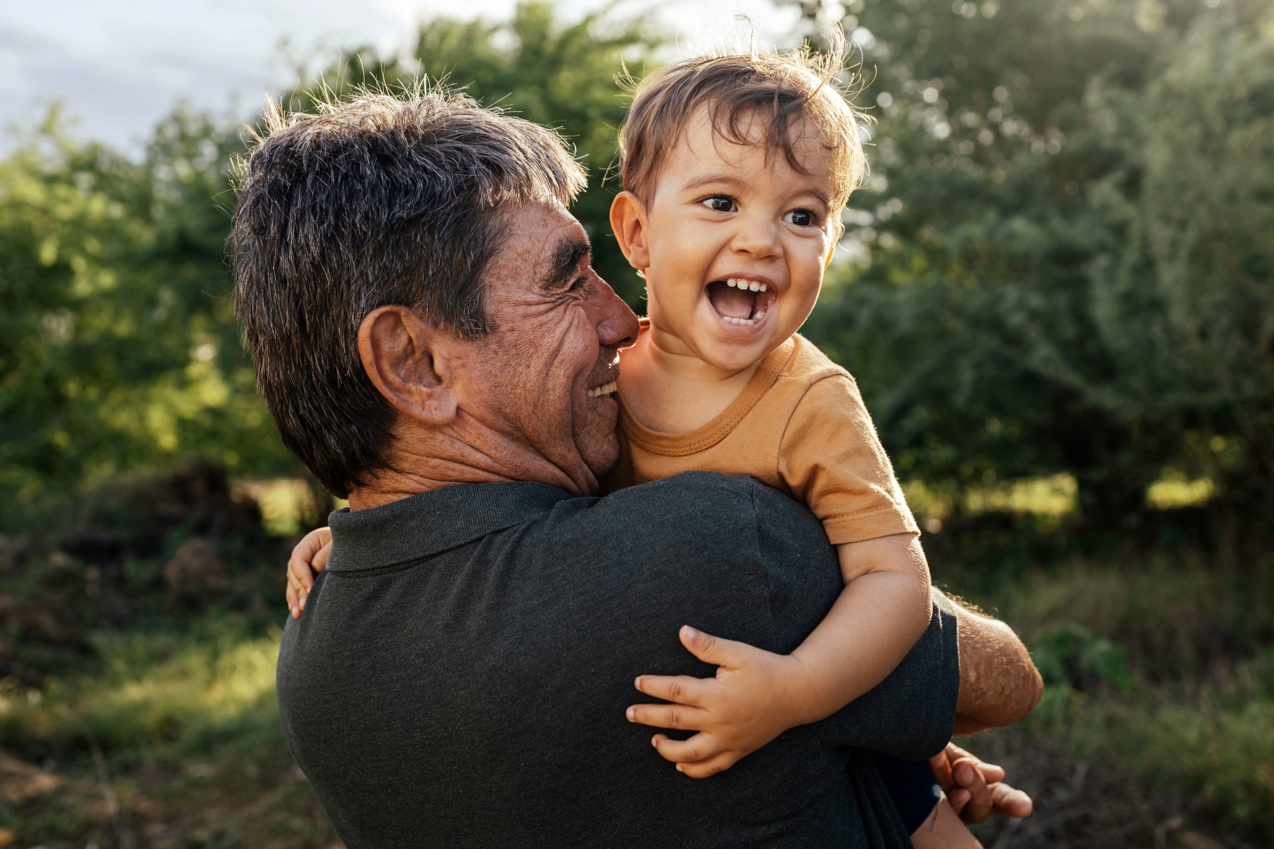 Foster Parent with young foster child smiling, sunshine on their backs.