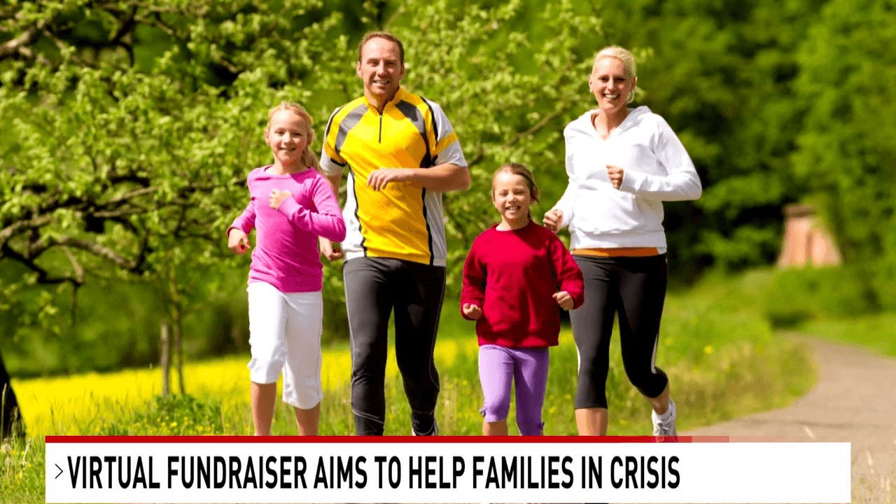 A family of four, consisting of two adults and two children, is jogging together outdoors on a paved path surrounded by greenery. They are dressed in athletic wear. A headline below the image reads, "Virtual Fundraiser Aims to Help Families in Crisis.